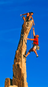 Rock climbing team reaching the summit.